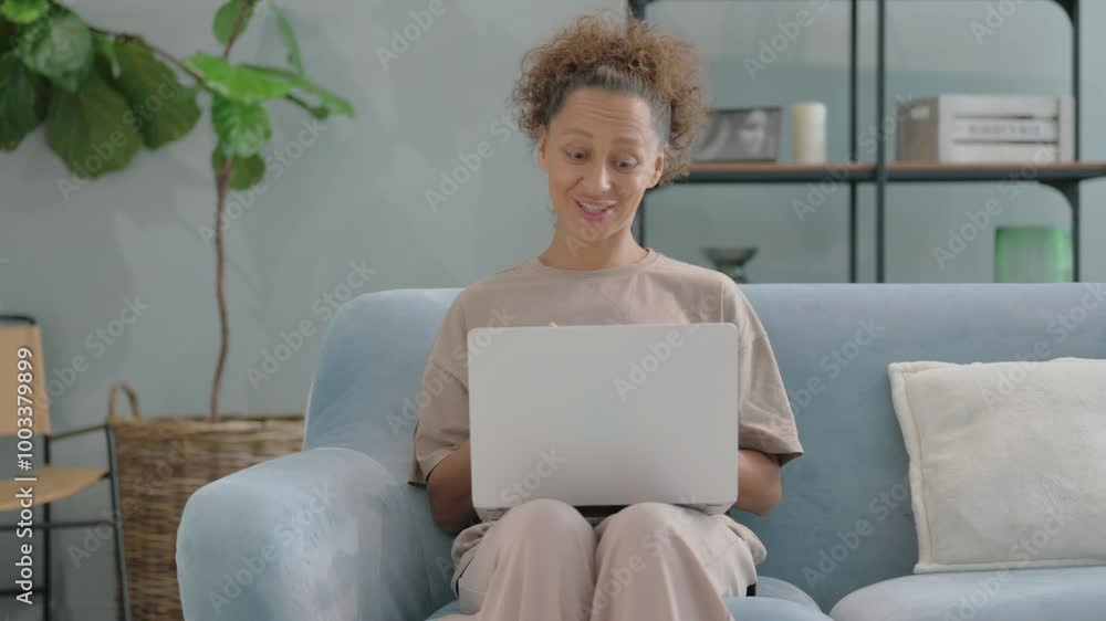 Online Video Chat on Laptop by Hispanic Woman Sitting on Sofa Online Video Chat on Laptop by Hispanic Woman Sitting on Sofa