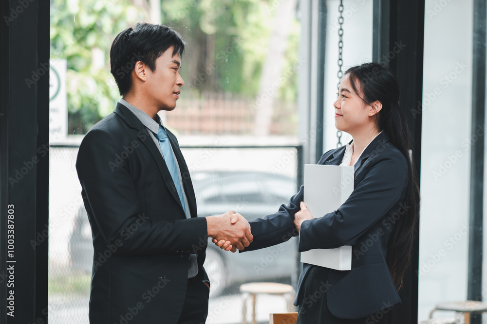 Two business professionals shaking hands in a modern office setting, symbolizing partnership and collaboration. Two business professionals shaking hands in a modern office setting, symbolizing partnership and collaboration.