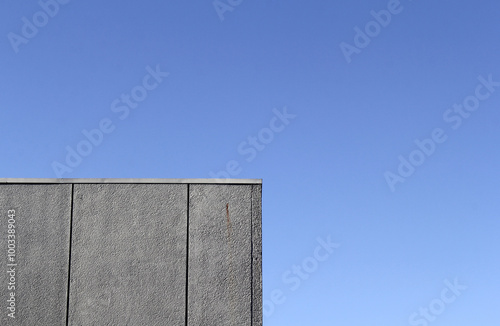 Concrete building wall against a clear blue sky background textured abstract