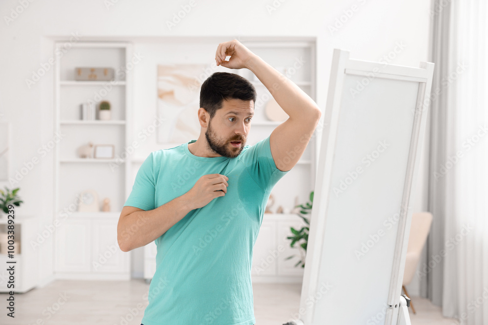 Emotional man in t-shirt before using deodorant at home Emotional man in t-shirt before using deodorant at home