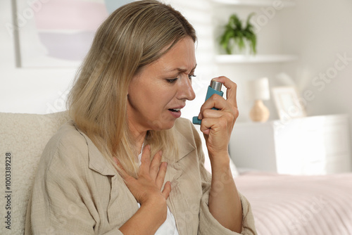 Woman using inhaler at home. Asthma treatment photo