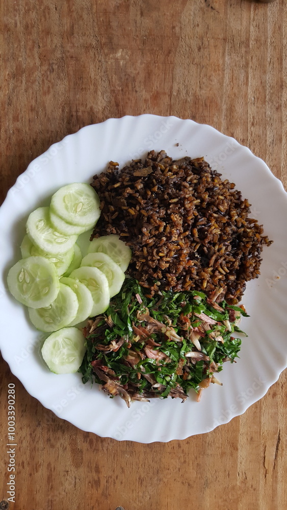 Prato branco com arroz integral preto, salada de couve, e pepino. Prato branco com arroz integral preto, salada de couve, e pepino.
