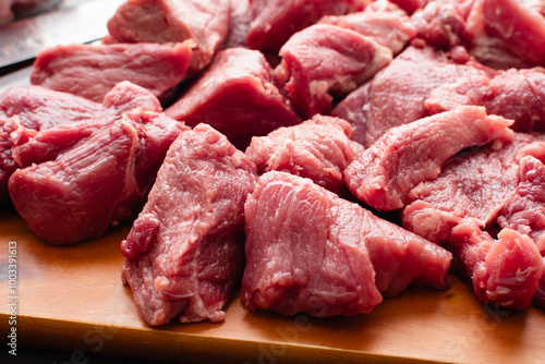 Close-up of Pork Shoulder Chunks On a Wooden Cutting Board: Pieces of Boston butt with a boning knife and a santoku knife on a wood chopping board photo