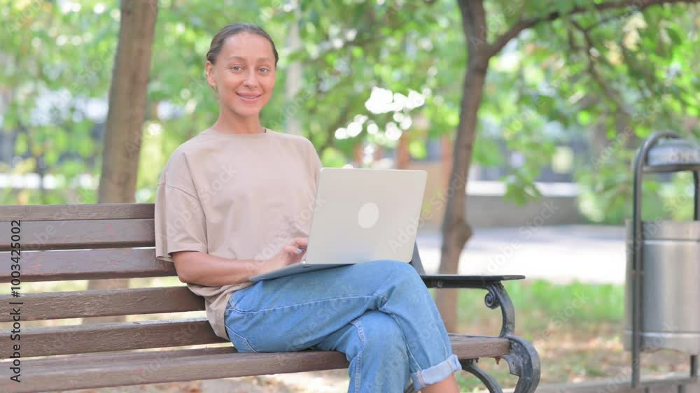 Young Hispanic Woman Smiling at Camera while Using Laptop Outdoor Young Hispanic Woman Smiling at Camera while Using Laptop Outdoor