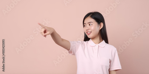 Young woman pointing with finger  smiling  pink shirt  pink background