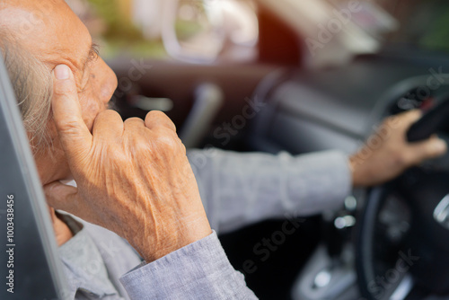 Tired middle aged man holding steering wheel in auto, presses hand to his head photo