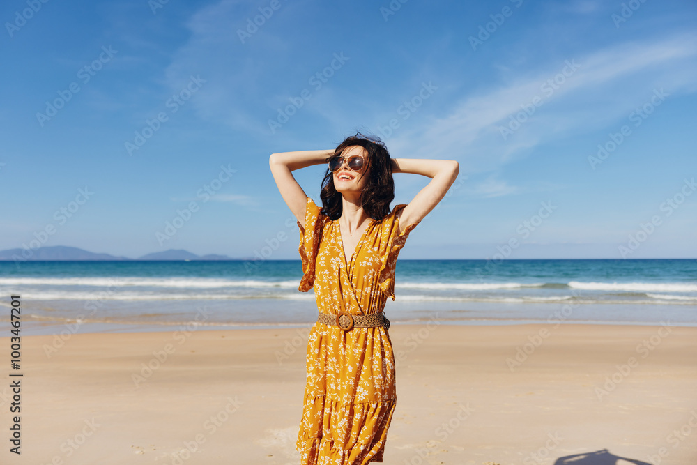 Young woman in a vibrant yellow dress feeling the breeze on a beautiful sandy beach Young woman in a vibrant yellow dress feeling the breeze on a beautiful sandy beach