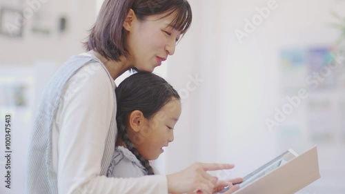 保育園で園児と絵本を見る女性の先生