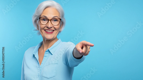 Attractive senior woman pointing with finger to side on blue background