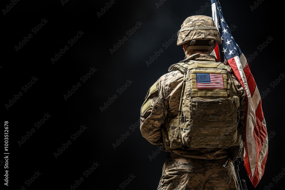 Fototapeta premium A soldier in camouflage uniform holding a US flag on a black background.