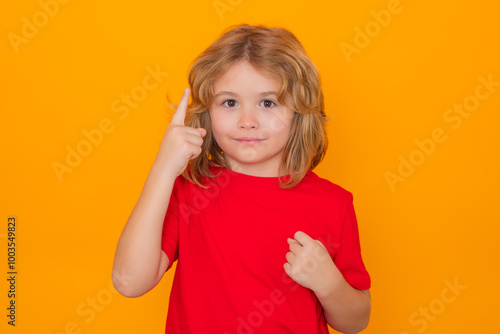 Child have idea on yellow isolated background. Child pointing up finger, on yellow background. Shocked kid pointing up, thinking.