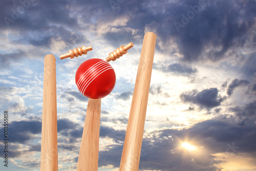 Fotografia Cricket ball hitting wicket stumps against blue sky background