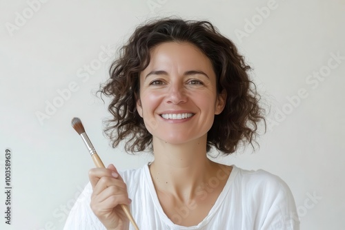 Smiling woman holding paintbrush, white isolate background