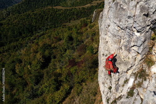Картината върху платно Aerial view of mountain rescuer rappelling on a rocky wall hanging on a rope
