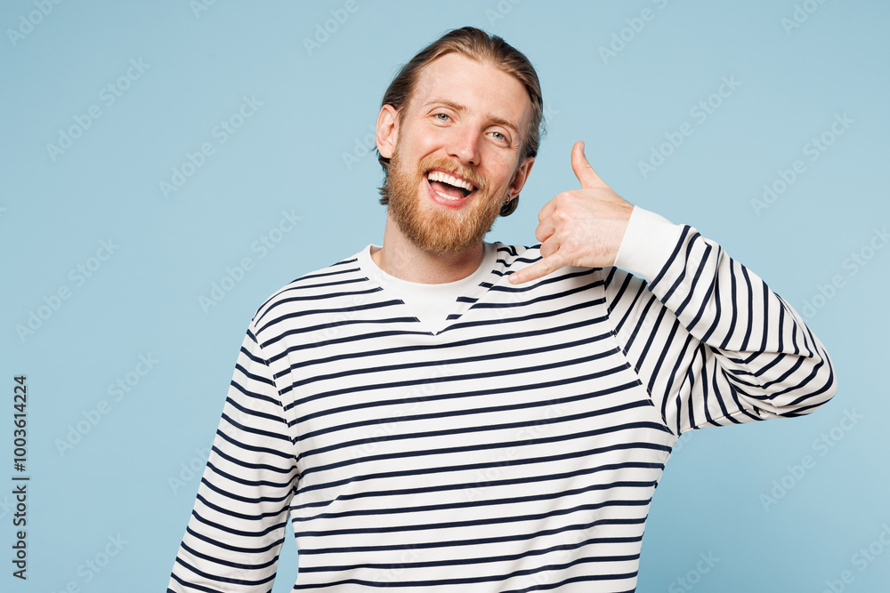 Young smiling happy fun man he wear striped sweatshirt casual clothes doing phone gesture like says call me back isolated on plain pastel light blue cyan background studio portrait. Lifestyle concept. Young smiling happy fun man he wear striped sweatshirt casual clothes doing phone gesture like says call me back isolated on plain pastel light blue cyan background studio portrait. Lifestyle concept.