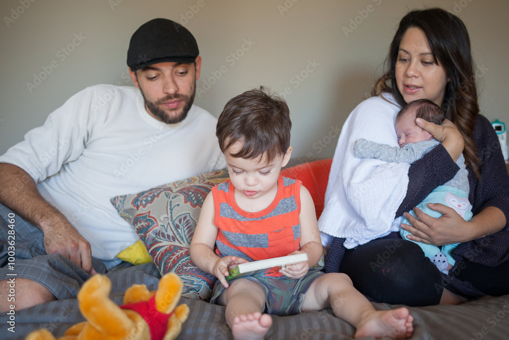 Family sitting together, toddler playing, a mother holding baby Family sitting together, toddler playing, a mother holding baby