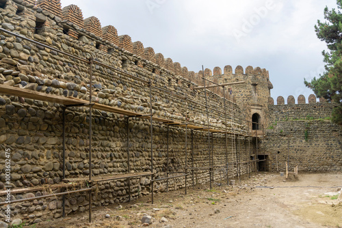 Fortress stone wall with a tower in the corner. Restoration work is underway photo