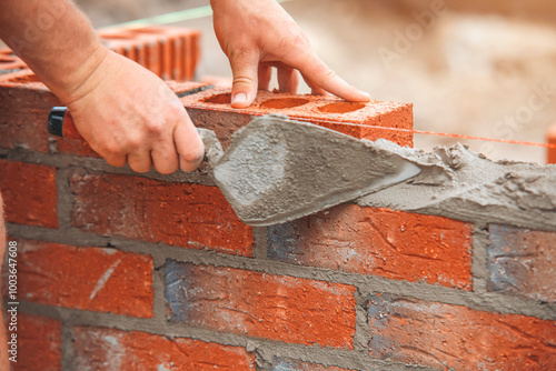 Crafting durable brick wall with skillful hands in sunlit construction site