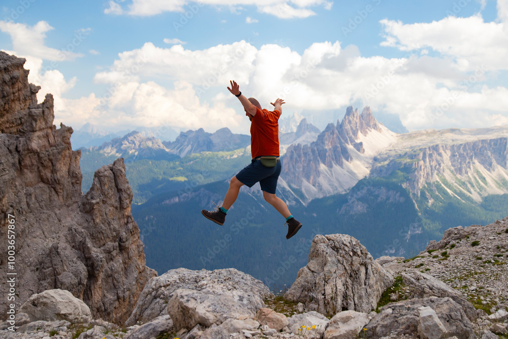 Young happy man high jumping on rocks in the Dolomite mountains. Young happy man high jumping on rocks in the Dolomite mountains.