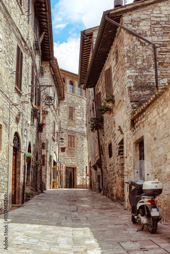 A charming cobblestone street in medieval Assisi, (Umbria, Italy), featuring ancient stone buildings and vibrant flower pots