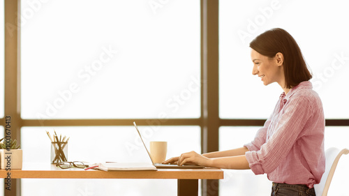 Online Education. Happy young woman studying on computer in modern library. Panorama, copy space