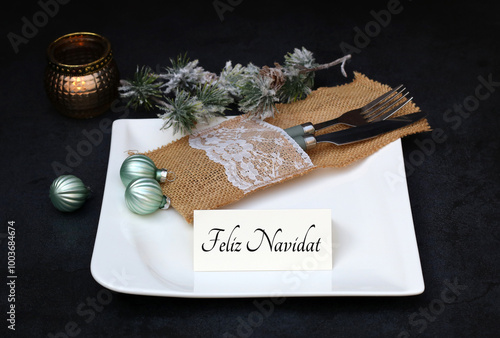 Mesa de Navidad festiva con platos y cubiertos. Texto Feliz Navidad en una tarjeta de sitio.