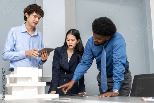 Architects engineers collaborating on building design project in modern office, diverse team of professionals female muslim architect and male engineers discussing architectural model of structure photo