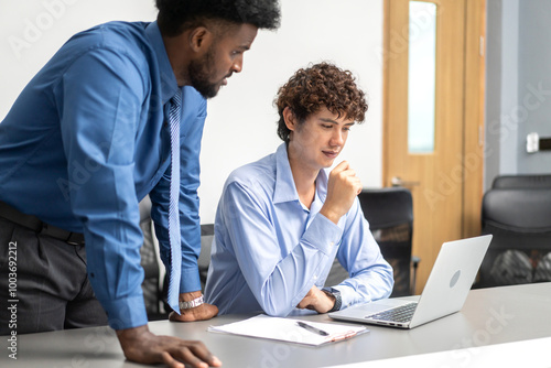 Diverse team of business professionals working on laptops during corporate meeting analyzing data and discussing project strategies, focused on collaboration, productivity and effective communication