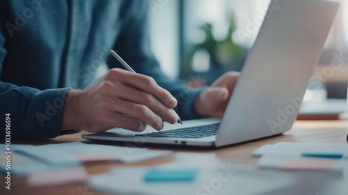 Person working on laptop, writing notes at a bright desk, peaceful environment