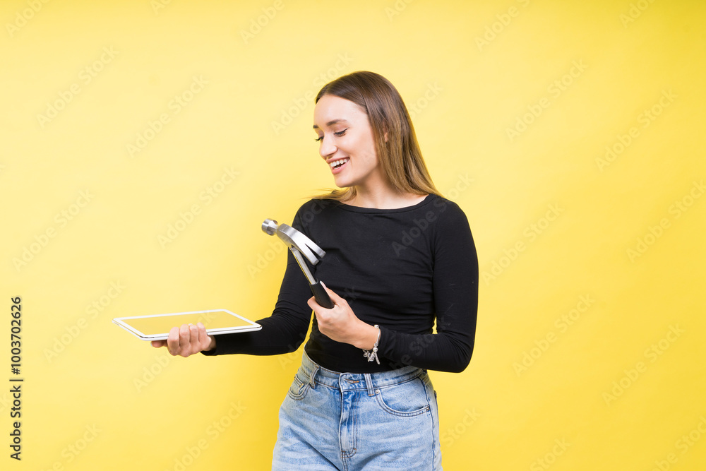 Woman with tablet and hammer, Studio lighting yellow background isolated, copy space Woman with tablet and hammer, Studio lighting yellow background isolated, copy space