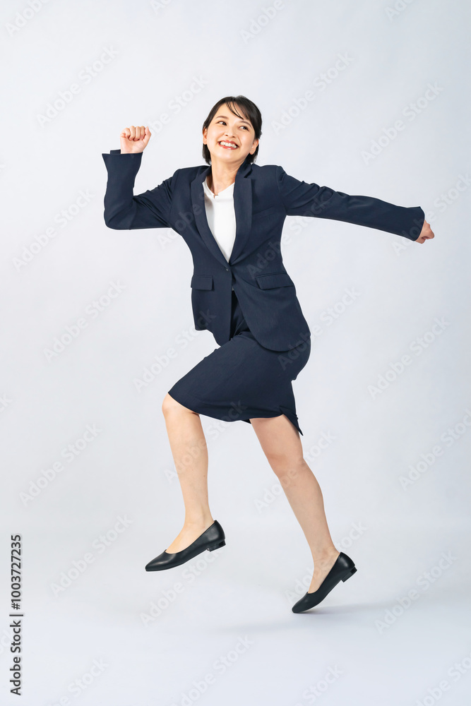 ジャンプするスーツを着た女性の全身写真