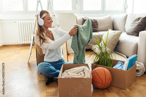 One woman, young lady moved into her new apartment, unpacking boxes alone. Cropped portrait of an attractive young woman packing a box while moving house.