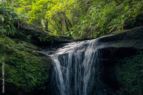 Wanggu waterfall in Pingxi, New Taipei City, peaceful water flowing down the river, and sunlight shines on the top. photo