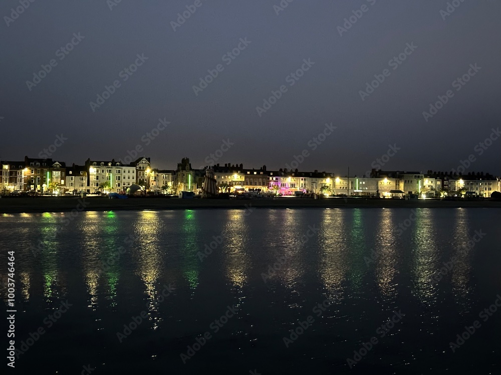 Night view of the town Weymouth with the lights reflected in Weymouth Bay water, England, United Kingdom, July 2023 Night view of the town Weymouth with the lights reflected in Weymouth Bay water, England, United Kingdom, July 2023