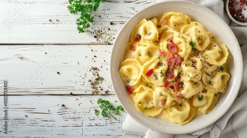 tortellini in creamy cheese sauce with crispy bacon in white bowl on white wood table landscape view from above photo