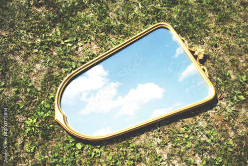 mirror in a meadow reflects a surreal sky with clouds, abstract concept photo