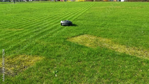 obotic lawnmower moving across large green field with striped grass photo