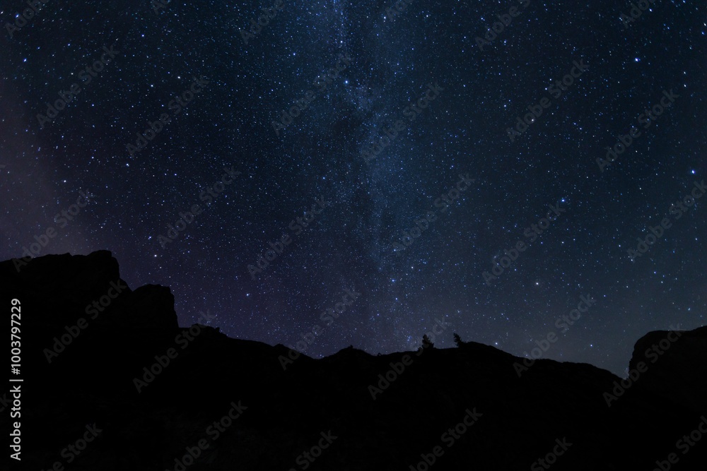 vista panoramica sul cielo stellato, sereno e scuro, di colore blu, con la via lattea visibile, da un ambiente di montagna tra Italia e Slovenia, durante una notte in estate
