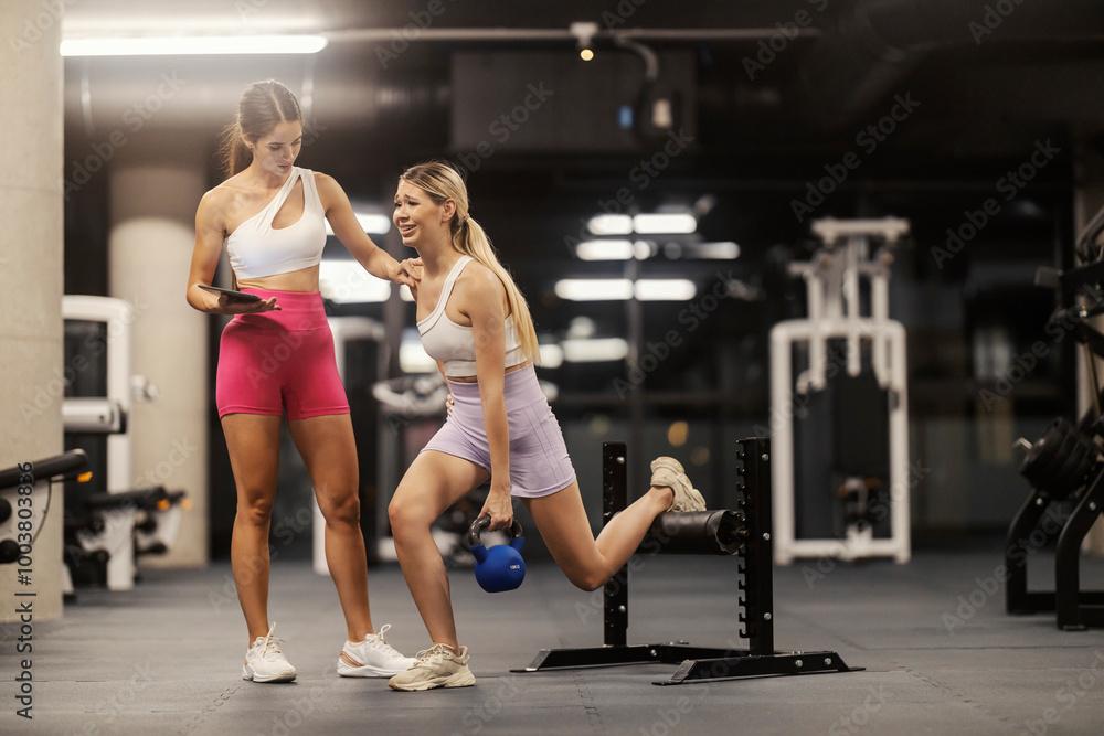 Exhausted sportswoman doing romanian squats at gym with her trainer encouraging her. Exhausted sportswoman doing romanian squats at gym with her trainer encouraging her.