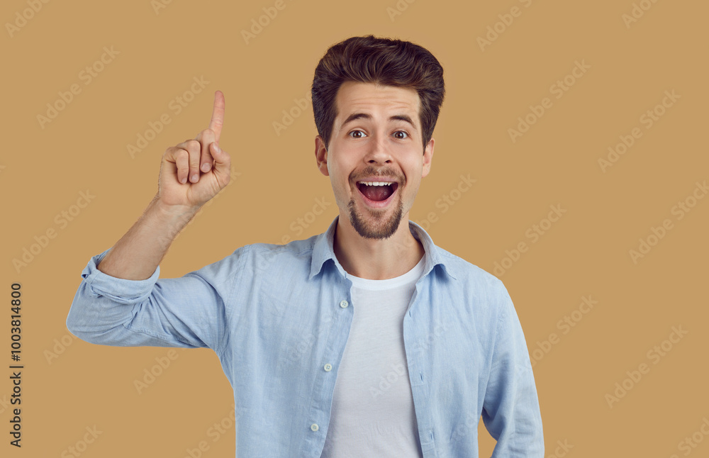 Portrait of emotional young man who having great idea, finding inspiration or solution to problem. Cheerful Caucasian guy with open mouth raises finger up isolated on beige background. Web banner. Portrait of emotional young man who having great idea, finding inspiration or solution to problem. Cheerful Caucasian guy with open mouth raises finger up isolated on beige background. Web banner.