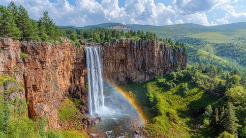 Majestic waterfall surrounded by lush greenery and vibrant rainbow.
