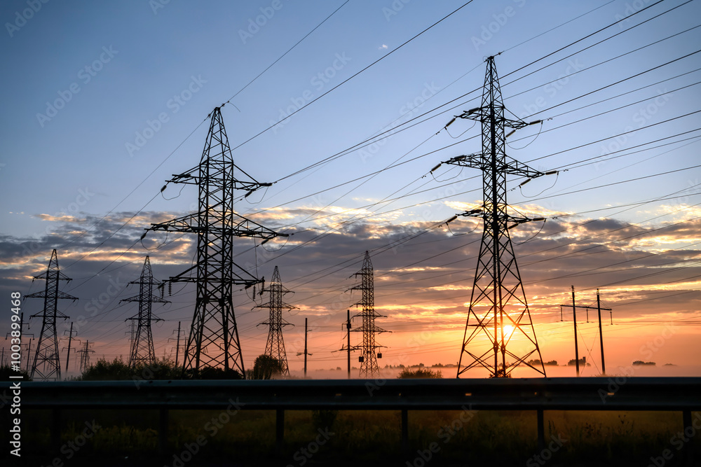 Fototapeta premium Metal supports of power lines at colorfull sunset sunrise, foggy morning.
