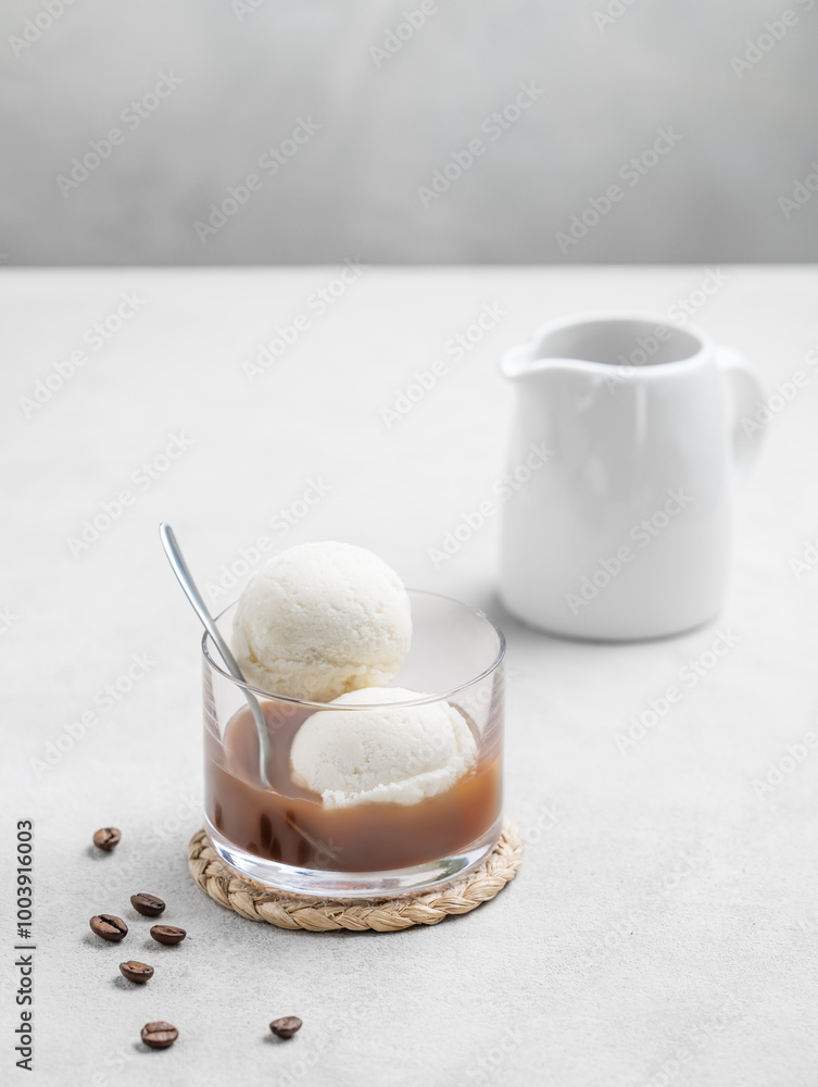 Affogato coffee with vanilla ice cream scoops and espresso in a glass on a light background with coffee beans and jug. Affogato coffee with vanilla ice cream scoops and espresso in a glass on a light background with coffee beans and jug.