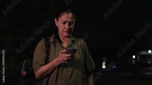 A woman stands alone, her expression a poignant blend of anticipation and frustration as she waits, , her body language and frequent checks of her phone conveying a sense of restlessness and concern