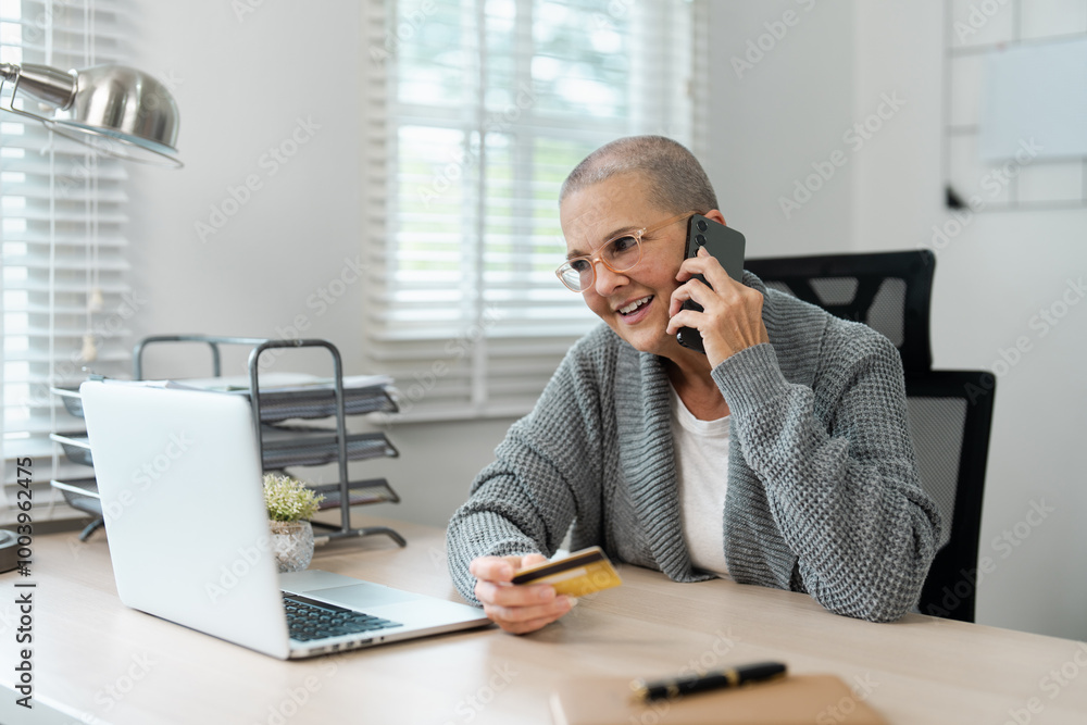 Senior Woman Shopping Online with Credit Card and Laptop While Talking on Phone at Home Office Senior Woman Shopping Online with Credit Card and Laptop While Talking on Phone at Home Office