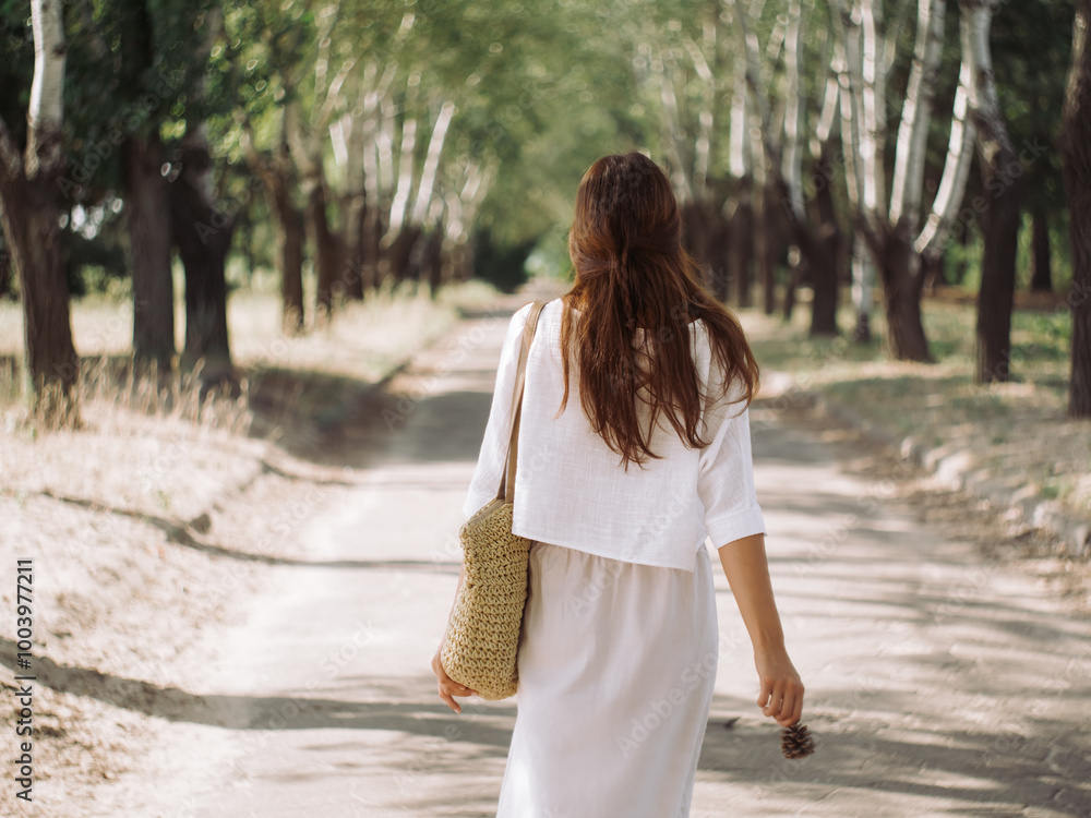 Back View of Woman Strolling on a Sunlit Tree-Lined Path Back View of Woman Strolling on a Sunlit Tree-Lined Path