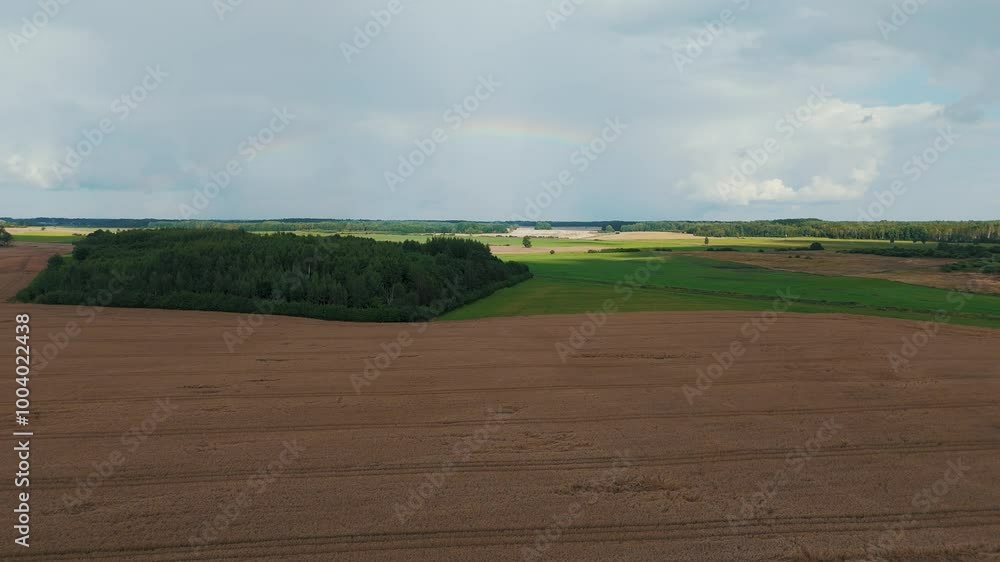 The Rainbow Over the Green Field After Storm With Rain, During Outumn, Aerial View Under Heavy Clouds Before Thunderstorm. Agriculture Landscape Many Crop Fields. Aerial 4k Shot The Rainbow Over the Green Field After Storm With Rain, During Outumn, Aerial View Under Heavy Clouds Before Thunderstorm. Agriculture Landscape Many Crop Fields. Aerial 4k Shot