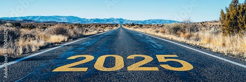 A desert road extends into the distant year 2025, flanked by mountains under a blue sky, representing a pathway to future achievements and aspirations. photo