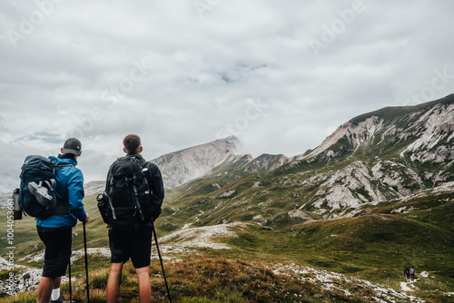 two hikers in the mountains looking at the beautiful landscape after taking a break