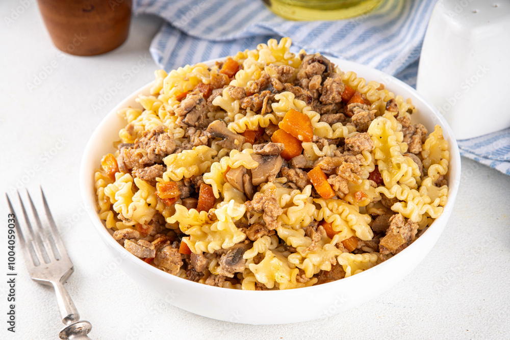 Easy homemade pasta with minced meat. One pot pasta with ground beef and autumn vegetables, in portioned plate on kitchen table Easy homemade pasta with minced meat. One pot pasta with ground beef and autumn vegetables, in portioned plate on kitchen table